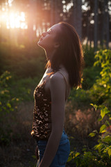 Beautiful young adult woman in forest at sunset