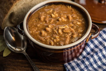 tripe stew sauce in brown ceramic pot on a wood table 
