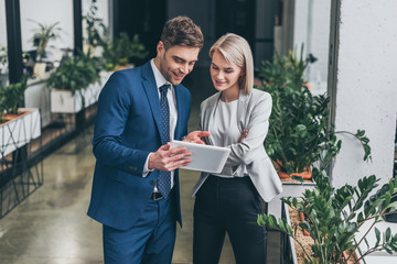 pretty businesswoman and handsome businessman using digital tablet together