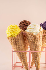 Assorted ice cream in sugar cones on pink background. Copy space.
