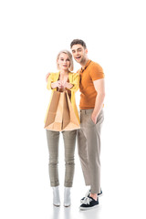 beautiful blonde woman holding paper bags while standing near handsome man and looking at camera isolated on white