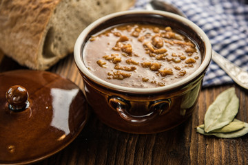 tripe stew sauce in brown ceramic pot on a wood table 