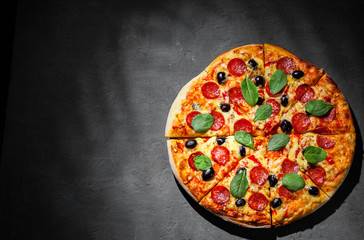 Pepperoni Pizza with Mozzarella cheese, salami, olive, pepper, Spices and Fresh spinach. Italian pizza on Dark grey black slate background