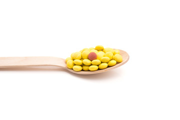 Yellow round vitamin pills in spoon isolated