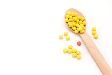 Yellow round vitamin pills in spoon isolated