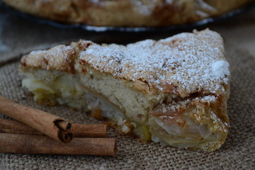 Apple pie with cinnamon. Wooden background.