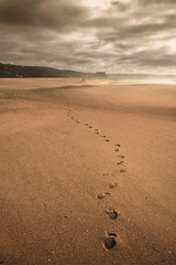 Lonely human footprints on a wide sandy beach in cloudy weather  in the city of Nazare in Portugal