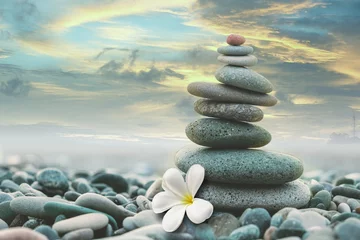  stone pyramid with a white magnolia flower on a pebble beach at sunset © Lana Kray