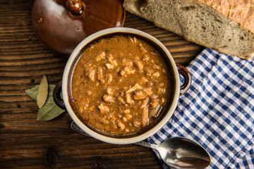 tripe stew sauce in brown ceramic pot on a wood table 