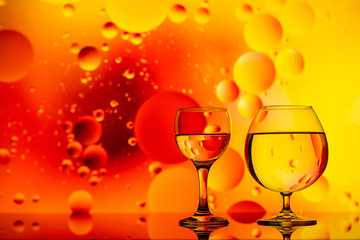 transparent glasses with water and oily drops on colorful background 