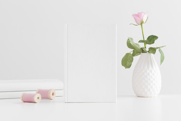 White book mockup with a pink rose and books on a white table.