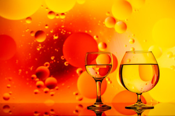 transparent glasses with water and oily drops on colorful background 