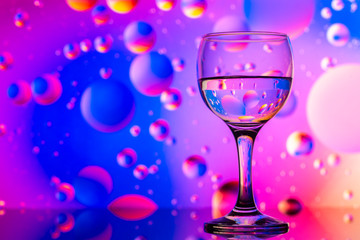 transparent glasses with water and oily drops on colorful background 