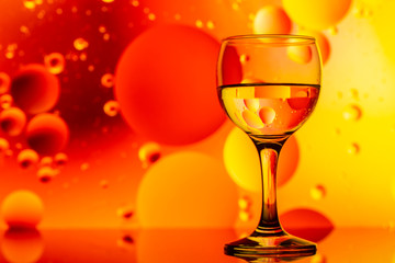 transparent glasses with water and oily drops on colorful background 