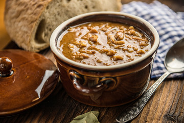tripe stew sauce in brown ceramic pot on a wood table 