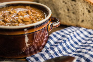 tripe stew sauce in brown ceramic pot on a wood table 