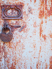The texture of the door and the lock of the old rusty red metal