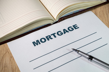 Mortgage and pen on bright wooden office desk.