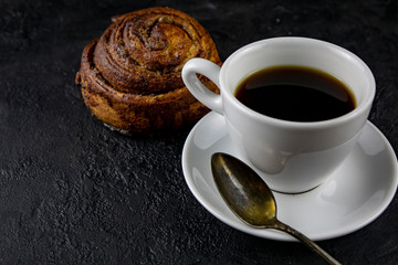 Sweet buns and cup of coffee on a dark stone background