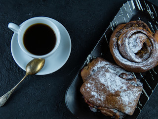 Sweet buns and a cup of coffee on a dark stone background