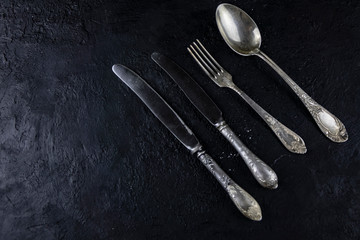 Vintage spoons, fork, kitchen knife on a rough stone background