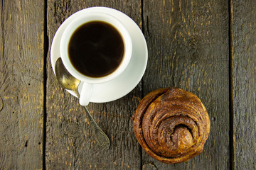 Cup of coffee and sweet buns on a rough wooden background