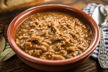 tripe stew sauce in brown ceramic pot on a wood table 