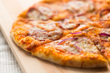 food, culinary and eating concept - close up of sliced homemade pizza on wooden table