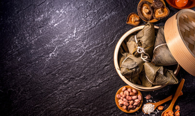 Close up, copy space, top view, flat lay. Famous asian chinese tasty handmade food in duan wu event, steamed rice dumplings shaped like pyramidal ingredient on black slate