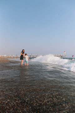 Mother and son walking on the beach. Sea horizon and blue sky. Family vacation at sea. Summer time sea vacation background 