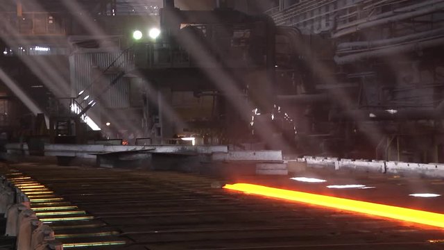 Fresh cast hot metal slab or rail. Conveyor line of a metal rolling mill. Hot steel rail on a conveyor in a metallurgical plant