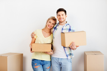 Fototapeta na wymiar mortgage, moving, people and real estate concept - happy couple with big cardboard boxes at new home