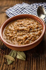 tripe stew sauce in brown ceramic pot on a wood table 