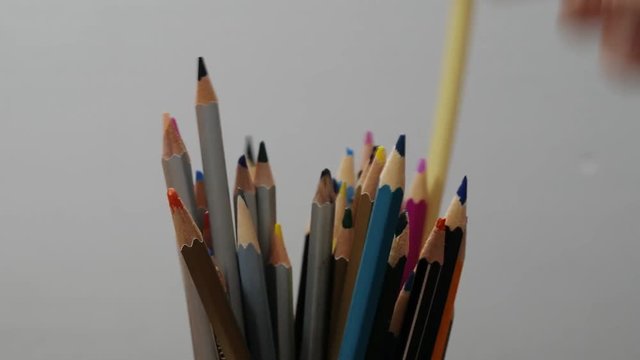Hand takes colorful pencils from stack , process of drawing, art, creation.