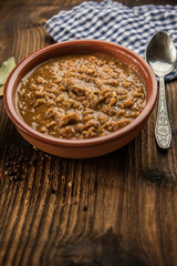 tripe stew sauce in brown ceramic pot on a wood table 