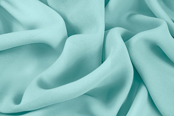 The texture of the satin fabric of green color for the background