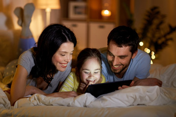 people and family concept - happy mother, father and little daughter with tablet pc computer in bed...