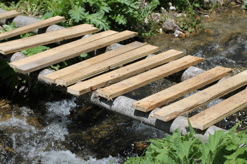 wooden bridge of planks over a stream in the forest