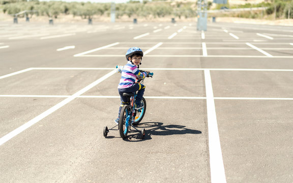 Little Kid On Bike Riddingin Parking Looking Back