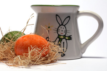 Osterschmuck mit bunt bemalten Eiern und einer Milchkanne mit Ostermotiv