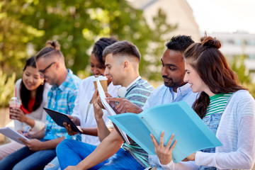 education and people concept - group of happy students with notebooks, tablet computer and takeaway drinks learning outdoors
