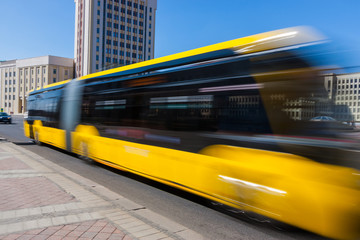 Motion blurred yellow bus on the avenue in the daytime.