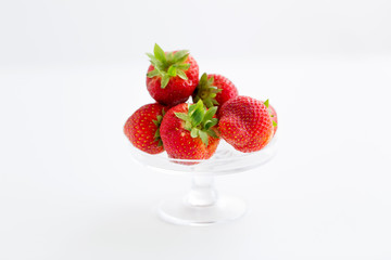 fruit, food and berries concept - strawberries on glass stand over white background