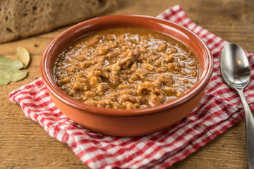 tripe stew sauce in brown ceramic pot on a wood table 