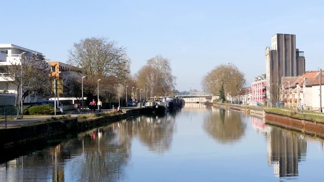 View on the Moselle river in the city of Nancy, north east France. Reflections on the water, blue sky. Filmed on a sunny day.