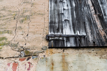 Old terracotta wall with cracks and crumbling plaster. Vintage shabby wooden surface on a door in old house. Shabby retro loft texture. 