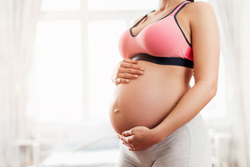 Fototapeta na wymiar Beautiful pregnant woman holding her baby belly – close up 