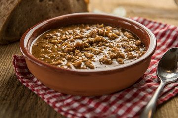 tripe stew sauce in brown ceramic pot on a wood table 