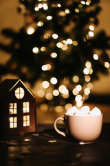Christmas coffee cup with marshmallows. Still life on dark background. New Year's lights and decorations