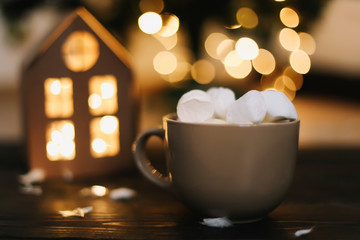 Christmas coffee cup with marshmallows. Still life on dark background. New Year's lights and decorations